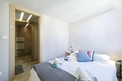a bedroom with a bed with white sheets and blue pillows at MY CASA - FRANCE 82 - 2 rooms -1 min from the Sea - Parking in Nice