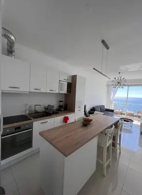 a kitchen with white cabinets and a wooden counter top at 2 Pièce - Promenade des Anglais in Nice