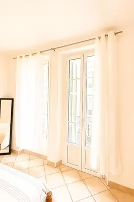 a bedroom with white curtains and a window at Charming & roomy apartment with balcony heart of Nice in Nice