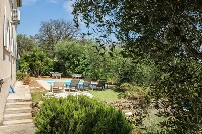 a backyard with a swimming pool and chairs and trees at Villa les Oliviers in La Gaude