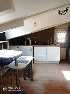 a kitchen with white cabinets and a table at Studio dernier étage vieux Nice centre in Nice