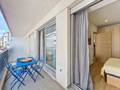 a balcony with a blue table and chairs and a bed at Nestor&Jeeves - MAYA TERRASSE - Centre ville in Nice