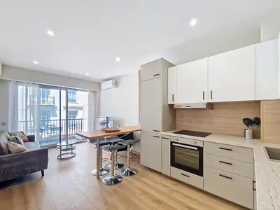 a kitchen with white cabinets and a table and a couch at Nestor&Jeeves - MAYA TERRASSE - Centre ville in Nice