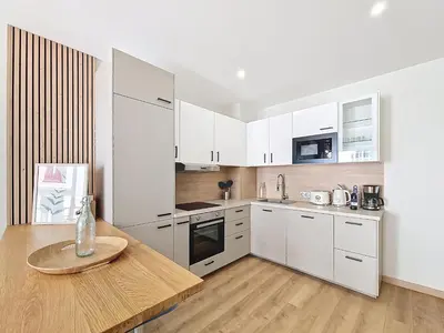 a kitchen with white cabinets and a wooden table at Nestor&Jeeves - MAYA TERRASSE - Centre ville in Nice