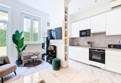 a kitchen with white cabinets and a tv on the wall at Nestor&Jeeves - OASIS - Terrace in the city in Nice