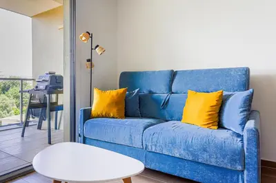a blue couch with yellow pillows in a living room at Ciel d'Azur - Climatisé piscine partagée in Saint-Laurent-du-Var