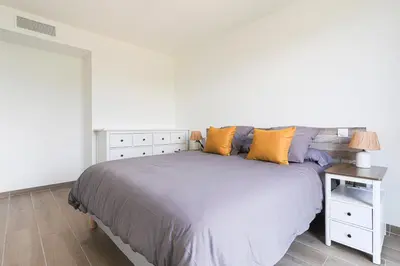 a white bedroom with a bed and a night stand at Ciel d'Azur - Climatisé piscine partagée in Saint-Laurent-du-Var