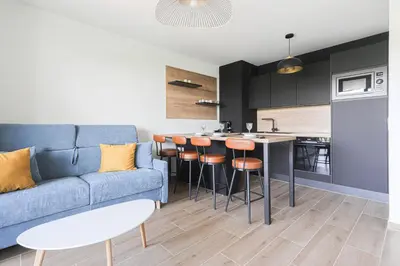 a living room with a blue couch and a kitchen at Ciel d'Azur - Climatisé piscine partagée in Saint-Laurent-du-Var