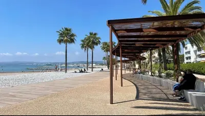 a boardwalk on a beach with palm trees and the ocean at SEA SIDE - Rooftop Pool SeaView in Saint-Laurent-du-Var