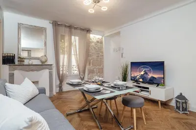 a living room with a couch and a table with a tv at Le Chic, appartement plein centre avec Climatisation in Nice