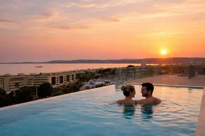 a man and a woman in a infinity pool with the sunset at Chez Valentina et Alexandre Port et plages à pied in Saint-Laurent-du-Var