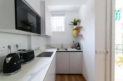 a kitchen with white cabinets and a sink and a tv at Oasis Azur 1 min from the beach in Nice
