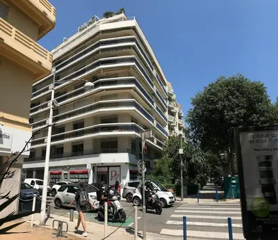a tall building with cars parked in a parking lot at Baquis in Nice