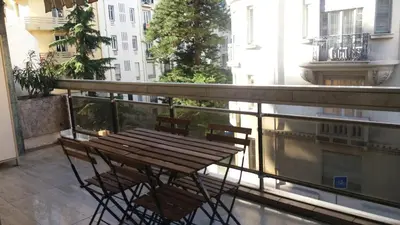 a balcony with a wooden table and chairs on a balcony at Baquis in Nice
