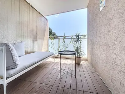 a balcony with a bed and a table in a room at Studio Neuf avec Terrasse et Aperçu Mer in Nice