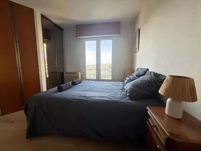a bedroom with a blue bed with a window at 3 Pieces st laurent du Var in Saint-Laurent-du-Var