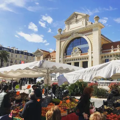 a market in front of a large building with fruit and vegetables at Magnifique appartement dans palais Niçois in Nice