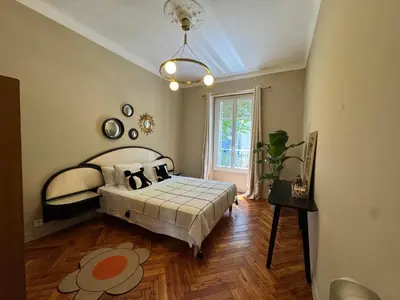 a bedroom with a bed and a large window at Magnifique appartement dans palais Niçois in Nice