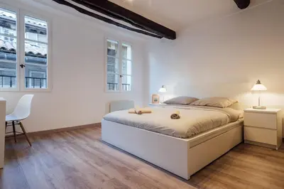 a white bedroom with a large bed and two windows at L'Authentic, charme dans la vieille ville avec climatisation in Nice