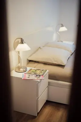 a bed with a table with a lamp and a book at L'Authentic, charme dans la vieille ville avec climatisation in Nice