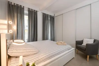 a white bedroom with a bed and a chair at Le Trendy, plein centre avec climatisation in Nice