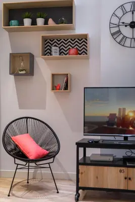 a chair with a red pillow sitting in front of a tv at L'Atelier, loft confortable dans la vieille ville, avec climatisation in Nice