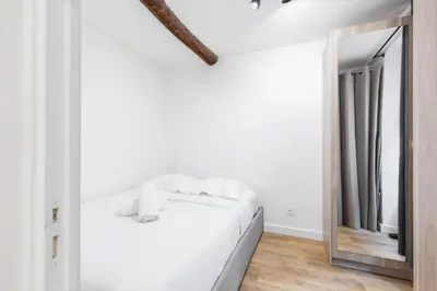 a bedroom with a white bed and a mirror at Charmant petit 2 pieces dans la vieille ville in Nice
