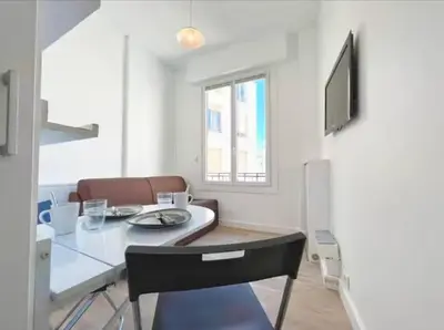 a dining room with a table and a television at Lumineux studio proche Jean Medecin in Nice