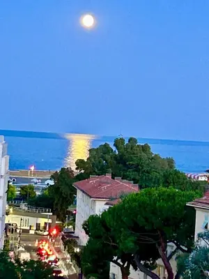 a full moon over the ocean and a city at Votre grand COCON Niçois Appart Vue Mer in Nice