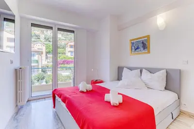 a bedroom with a large bed with a red blanket at PANORAMIC ESTEREL AP4475 By Riviera Holiday Homes in Villefranche-sur-Mer
