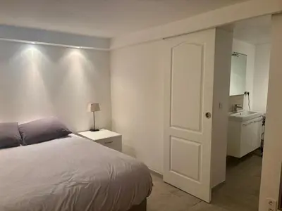a bedroom with a bed and a bathroom with a sink at Appartement terrasse jacuzzi in Nice
