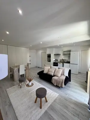 a living room with a black couch and a kitchen at Charmant 2pcs - 5min des plages in Cagnes-sur-Mer