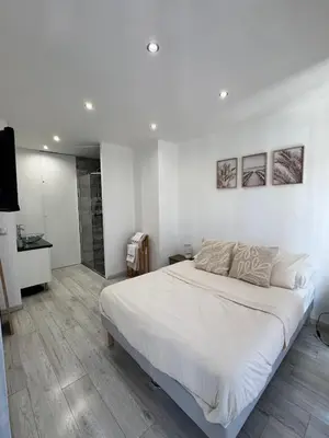 a white bedroom with a large bed and a television at Charmant 2pcs - 5min des plages in Cagnes-sur-Mer