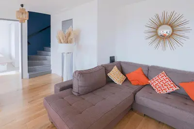 a living room with a brown couch with orange pillows at Villa Bleu Azur - Élégance Privée avec Vue Mer & Montagne in Cagnes-sur-Mer