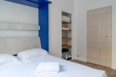 a bedroom with a white bed with a blue headboard at 2 pièces - Clim - tram à 5' centre à 15' in Nice