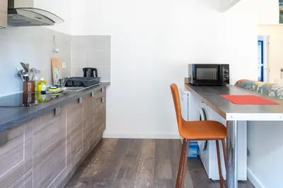 a kitchen with a counter and a table with a microwave at 2 pièces - Clim - tram à 5' centre à 15' in Nice