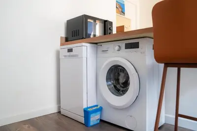 a white washing machine with a microwave on top of it at 2 pièces - Clim - tram à 5' centre à 15' in Nice