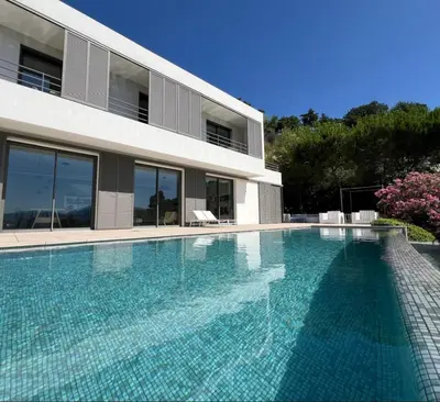 a swimming pool in front of a house at Contemporary Villa with Sea View, Infinity Swimming pool, Gym , Cinema room,Lift in Nice