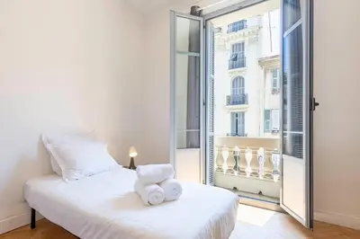 a bedroom with a white bed and a large window at Grand appartement climatisé centre ville Nice in Nice