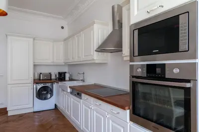 a kitchen with white cabinets and a washer and dryer at Grand appartement climatisé centre ville Nice in Nice
