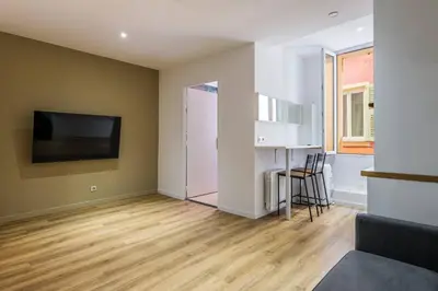 an empty living room with a table and a television at Appartement cosy au coeur de la vieille ville in Nice