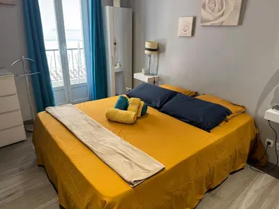 a bed with yellow sheets and blue pillows in a bedroom at Agreable 2 pièces Nice liberation in Nice
