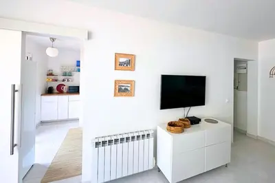 a white living room with a flat screen tv on a wall at Magnifique Studio Le Renoir proche mer in Nice