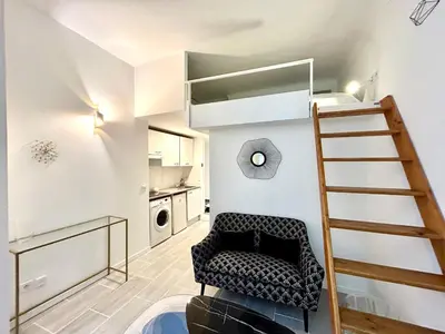 a living room with a chair and a stair case at Studio close to Main Street and Train Station in Nice