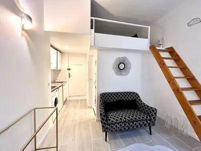 a living room with a chair and a staircase at Studio close to Main Street and Train Station in Nice