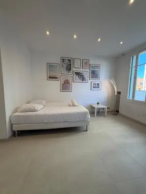 a living room with a white couch and pictures on the wall at Plein centre clim, proche gare et tramway in Nice