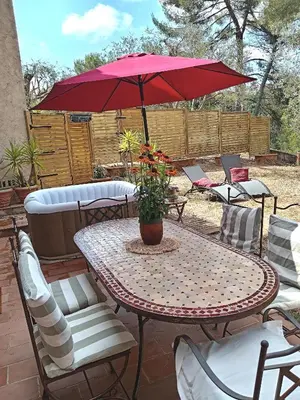 a patio table and chairs with a red umbrella at A la campagne aux portes de Nice in Falicon