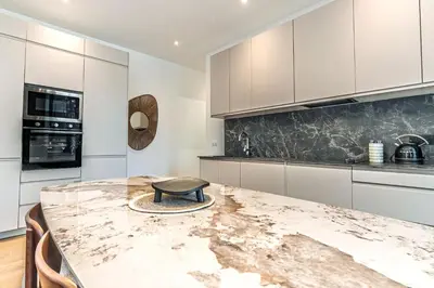 a kitchen with white cabinets and a marble counter top at Magnifique appartement - Jacuzzi - Port de Nice in Nice