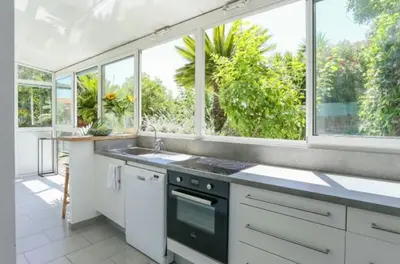 a kitchen with white cabinets and windows and a sink at Jardin tropical, parking, climatisation in Nice