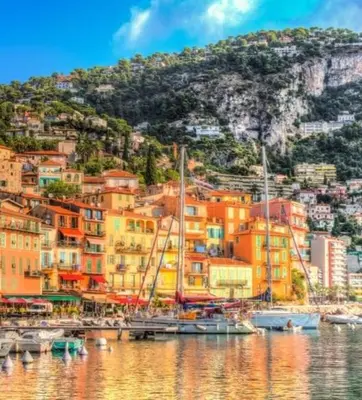 a group of colorful houses on a hill next to the water at Jardin tropical, parking, climatisation in Nice